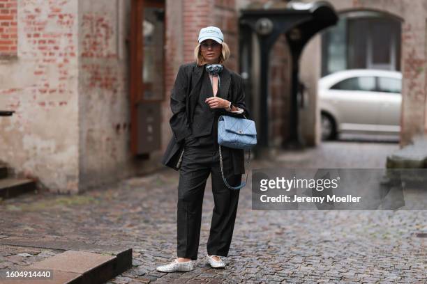 Karin Teigl seen wearing Munthe grey checked blazer jacket with matching suit pants, Sporty & Rich light blue cap, gold pendant earrings, Andy Wolf...