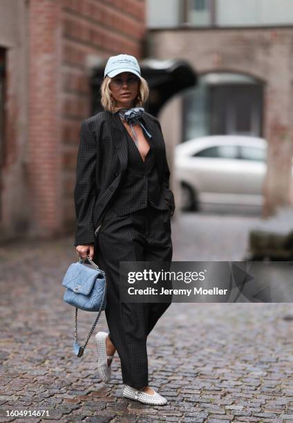 Karin Teigl seen wearing Munthe grey checked blazer jacket with matching suit pants, Sporty & Rich light blue cap, gold pendant earrings, Andy Wolf...