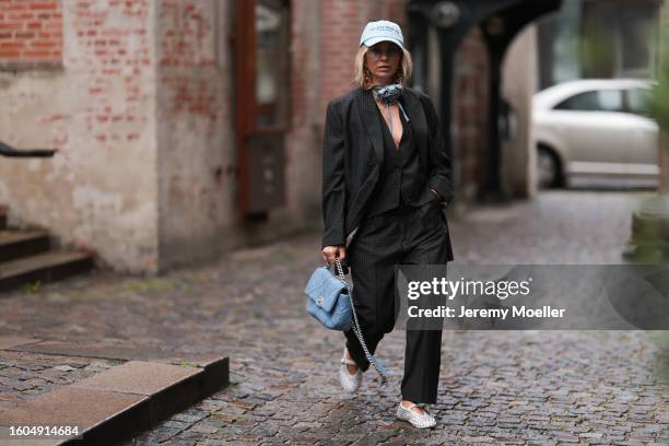 Karin Teigl seen wearing Munthe grey checked blazer jacket with matching suit pants, Sporty & Rich light blue cap, gold pendant earrings, Andy Wolf...