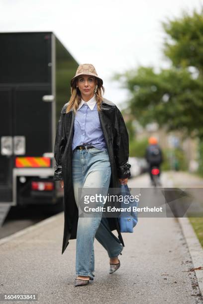 Guest wears a beige and brown GG. Monogram print pattern denim bob hat from Gucci, pearls pendant earrings, a blue and white striped print pattern...