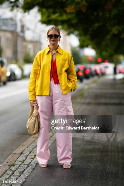 Guest wears black sunglasses, a silver rhinestones necklace, a neon red buttoned wool cardigan, a yellow zipper denim jacket, pale pink nylon large...