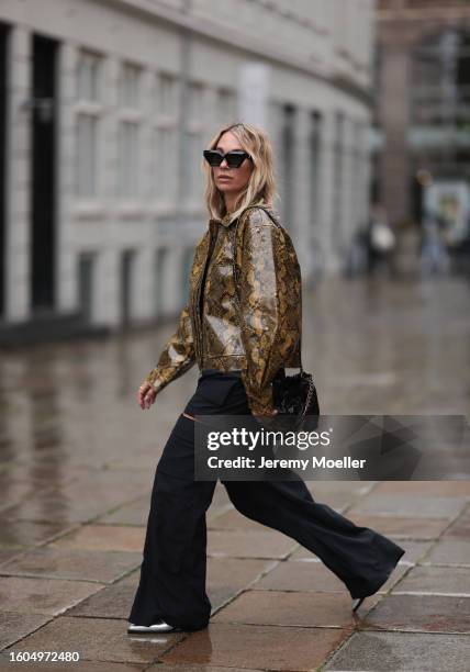 Karin Teigl seen wearing Louis Vuitton black sunglasses, Holzweiler yellow brown snake print pattern shiny varnished leather jacket, Holzweiler black...