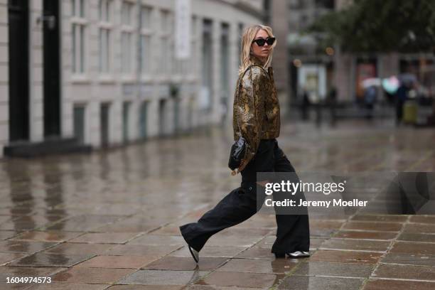 Karin Teigl seen wearing Louis Vuitton black sunglasses, Holzweiler yellow brown snake print pattern shiny varnished leather jacket, Holzweiler black...