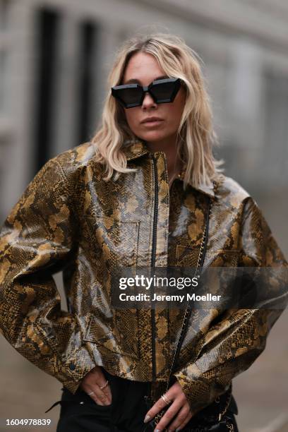 Karin Teigl seen wearing Louis Vuitton black sunglasses, Holzweiler yellow brown snake print pattern shiny varnished leather jacket, Holzweiler black...