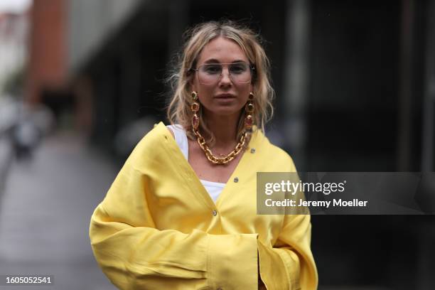 Karin Teigl seen wearing Andy Wolf light blue transparent pilot sunglasses, gold pendant earrings, Louis Vuitton gold statement chain necklace, white...