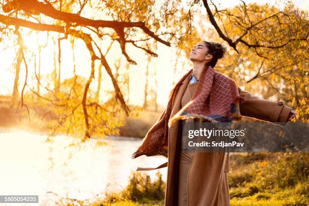 beautiful young woman enjoying a carefree autumn day outdoors - woman in a shawl stockfoto's en -beelden