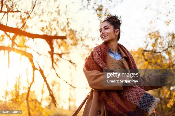 beautiful young woman enjoying a carefree autumn day outdoors - hair bun scarf woman stock pictures, royalty-free photos & images