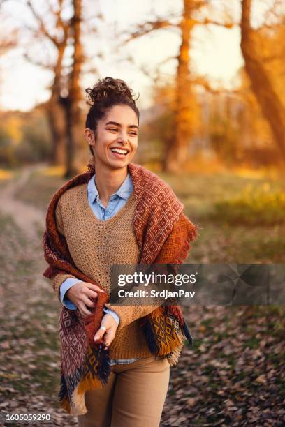 beautiful young woman enjoying a carefree autumn day outdoors - hair bun scarf woman stock pictures, royalty-free photos & images