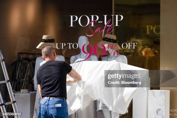 An employee prepares a discount sale offer window sign on Bond Street in London, UK, on Thursday, Aug. 17, 2023. The Office for National Statistics...