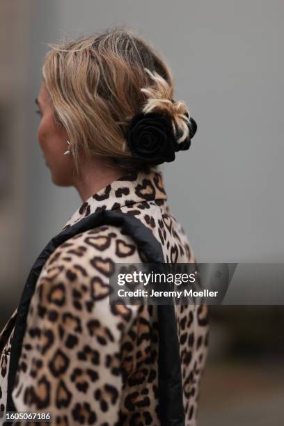 Karin Teigl seen wearing H&M beige / brown leopard pattern long coat, black rose hair clip, Vee Collective black nylon crossbody bag, during the...