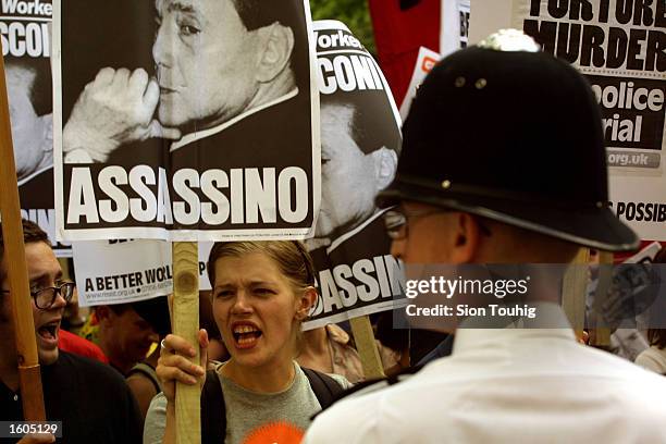 Protesters carry banners accusing Italian President Sylvio Berlusconi of murder July 28, 2001 at a demonstration outside the Italian embassy in...