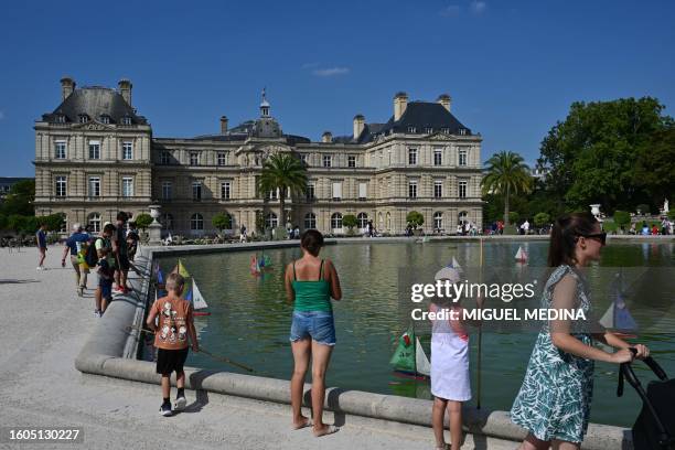 Children play with toy boats on the Grand Basssin in front of the Luxembourg Palace at the Luxembourg Gardens in Paris, on August 17, 2023.