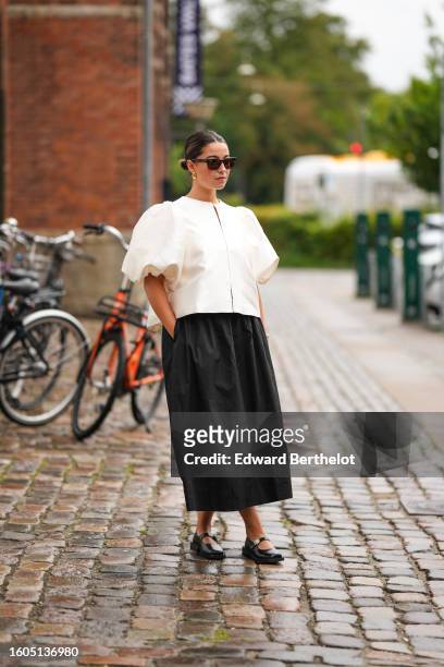 Guest wears black sunglasses, a pale yellow puffy short sleeves blouse, a black nylon long skirt, a beige wickers handbag, black shiny leather...