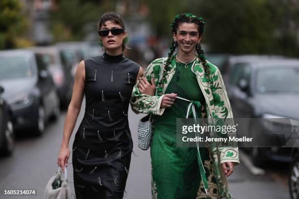 Lea Naumann seen wearing Prada black sunglasses, green flower rhinestones pendant earrings, black sleeveless high neck long dress with tassel...