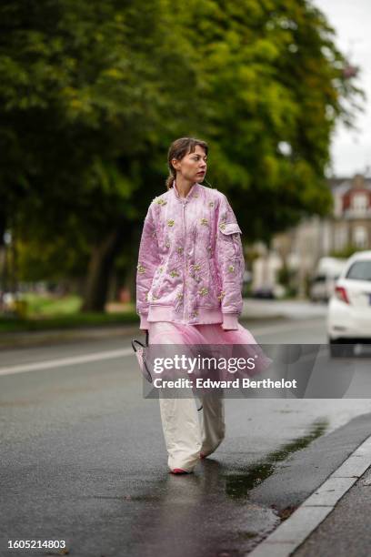 Guest wears a white t-shirt, a pale pink with embroidered white pearls and green pattern zipper oversized bomber coat, a pale pink tulle ruffled...