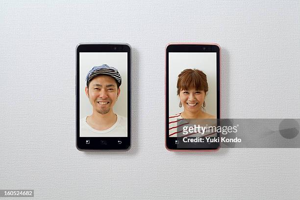 smiling faces and a smart phones. - side by side foto e immagini stock