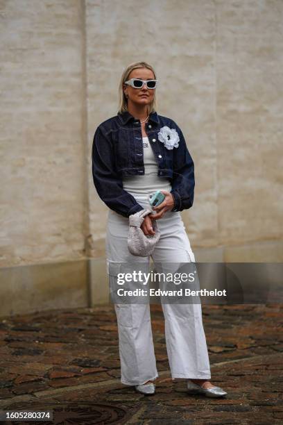 Guest wears white with black print pattern sunglasses from Prada, silver earrings, a silver necklace, a white tank-top from Loewe, a navy blue...