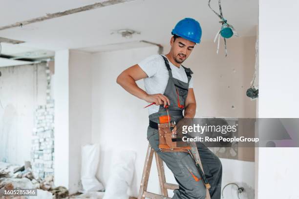 apartment renovation underway with helmet-wearing worker - broken light bulb stock pictures, royalty-free photos & images