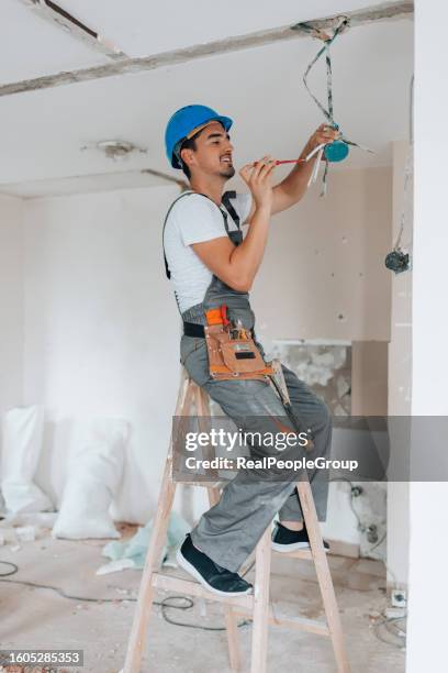 ein junger bauarbeiter arbeitet während der renovierung an der wohnungsdecke - broken lamp stock-fotos und bilder