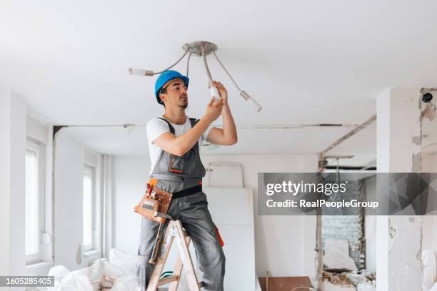 construction worker contributes to ceiling enhancement in the renovation - broken light bulb stock pictures, royalty-free photos & images