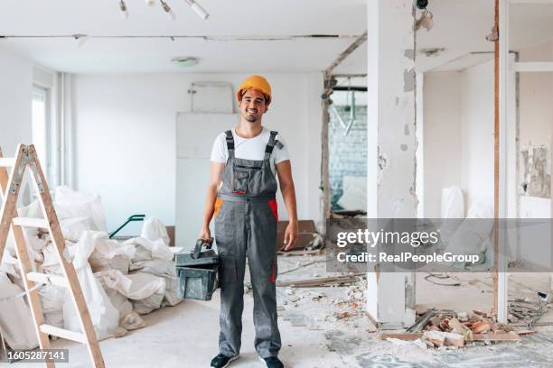 portrait of young construction worker amid apartment renovation - construction worker pose stock pictures, royalty-free photos & images