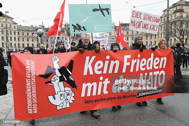 People hold signs as they demonstrate during a protest against the Munich Security Conference in the city centre on February 2, 2013 in Munich,...