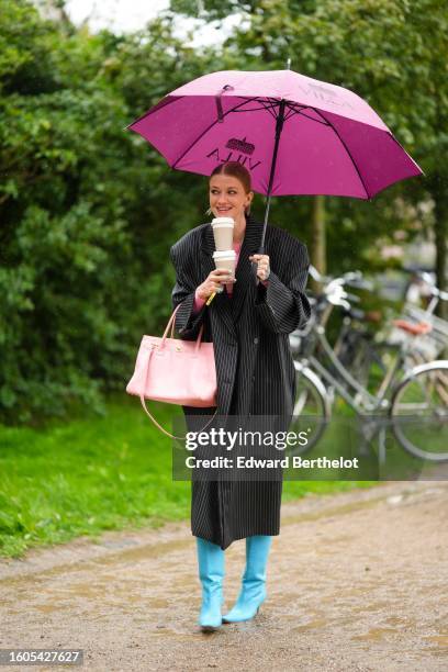 Marianne Theodorsen wears gold micro earrings, a gold and pink stones necklace, a pale pink with red and purple print pattern / white embroidered...