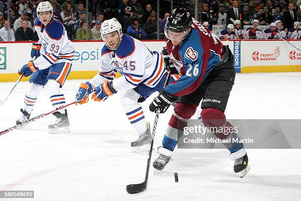 Paul Stastny of the Colorado Avalanche tries to control the puck against Mark Fistric and Ryan Smyth of the Edmonton Oilers at the Pepsi Center on...