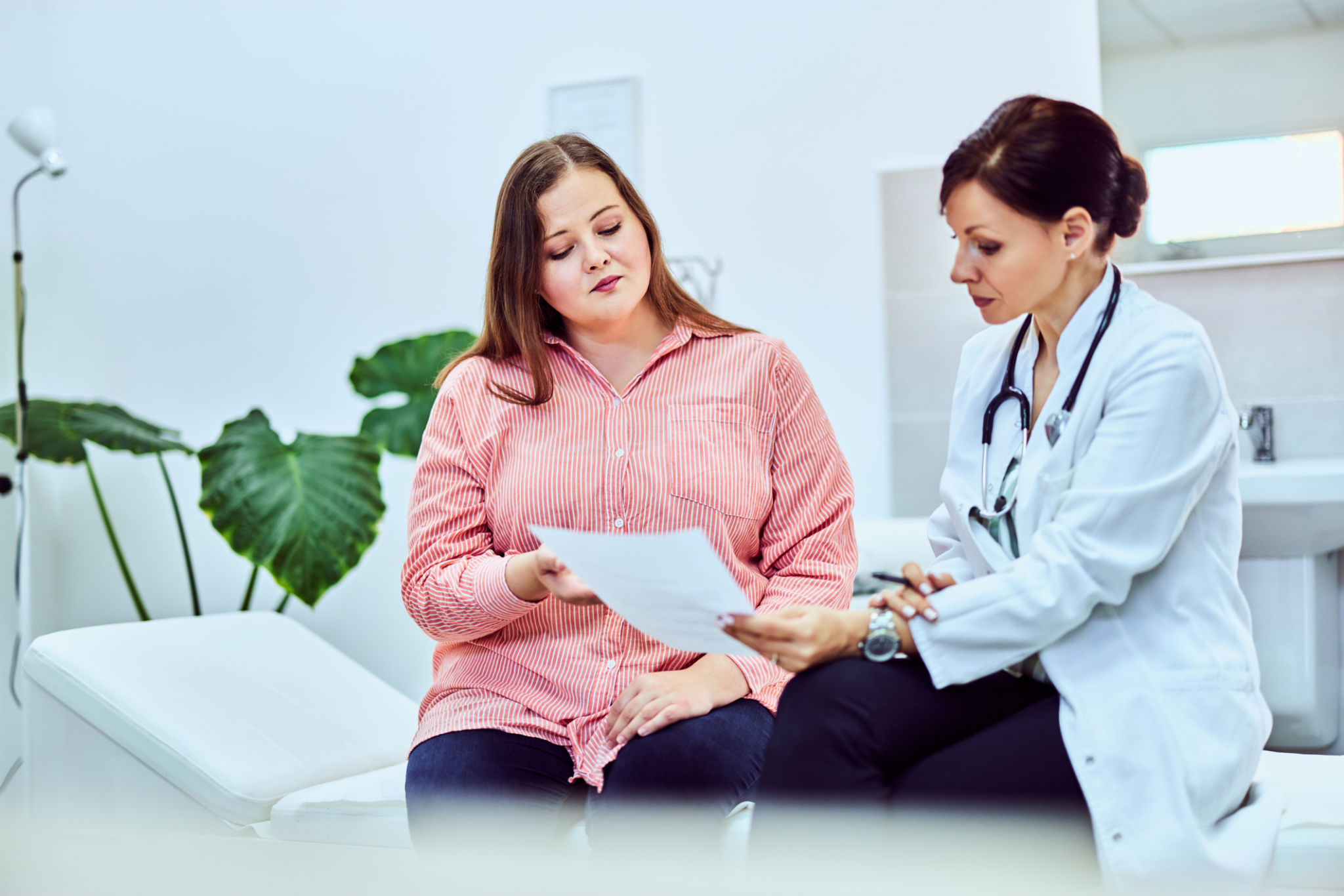 Una mujer con bastante sobrepeso en una consulta nutricionista, hablando de un plan de dieta. Una mujer con bastante sobrepeso en una consulta nutricionista, hablando de un plan de dieta.