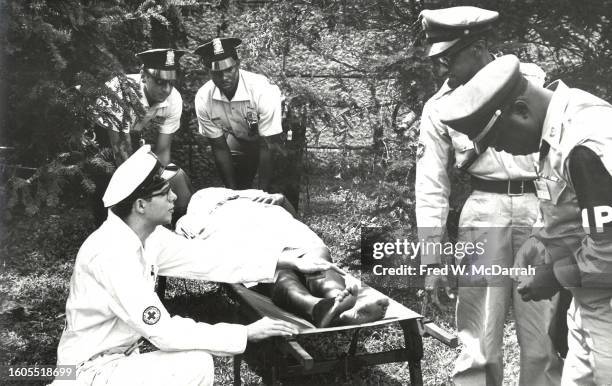 View of a medic, police officers, and military police around person who lies on a stretcher during the March on Washington for Jobs and Freedom,...