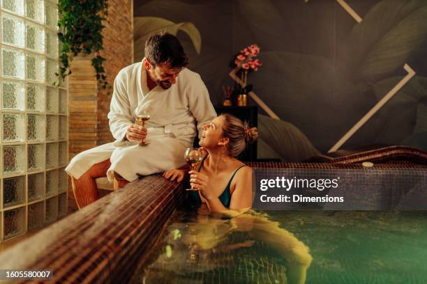 a romantic couple drinks wine at spa center - bathrobe stock pictures, royalty-free photos & images