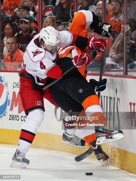 Tye McGinn of the Philadelphia Flyers is checked into the boards behind the net by Jamie McBain of the Carolina Hurricanes on February 2, 2013 at the...
