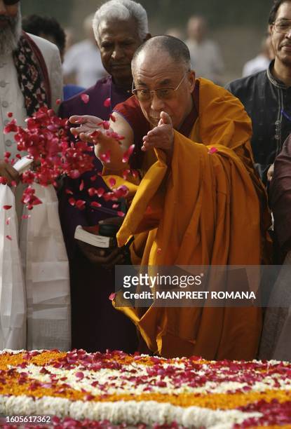 Tibetan spiritual leader The Dalai Lama throws rose petals at Raj Ghat, The Memorial to Mahatma Gandhi in New Delhi on March 29 to attend a public...