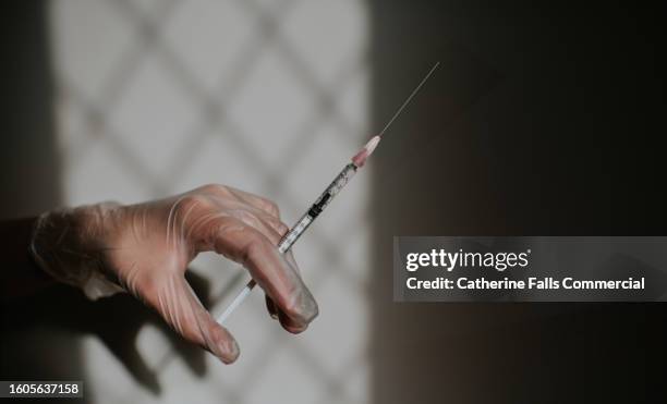 simple image of a gloved hand holding a medical syringe - surgical mask and gloves stock pictures, royalty-free photos & images