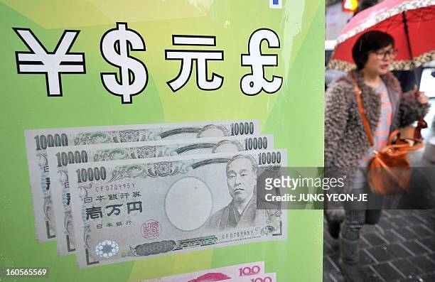 SKorea-Japan-economy-trade-forex,FOCUS by Jung Hawon This photo taken on February 1, 2013 shows a woman walking past a currency exchange sign...