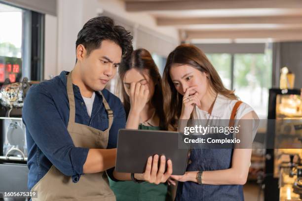 three barista entrepreneur team meeting at coffee shop. young asian male and female cafe employees seriously having discussion with tablet computer - overworked waitress stock pictures, royalty-free photos & images