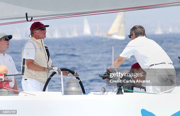 King Juan Carlos of Spain, left, steers a yacht during the first day of the 20th "Copa del Rey" regatta July 31, 2001 at Palma de Mallorca Island,...