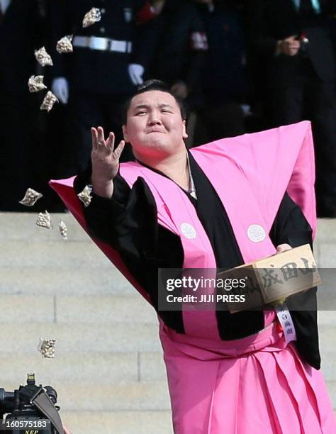 Sumo grand champion Hakuho of Mongolia throws small bags containing beans during a bean-throwing ceremony to drive away evil and bring good luck at...