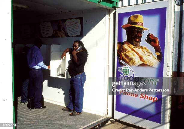 An unidentified man uses a phone in a container sponsored by Vodacom, the British mobile phone telecom operator March 14, 2001 in Khayelitsha, a poor...