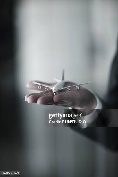 a plane model on a business man's hand - toy airplane stock-fotos und bilder