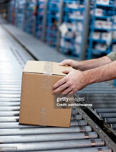 hands getting a box off of conveyer belt - boxes conveyor belt stockfoto's en -beelden