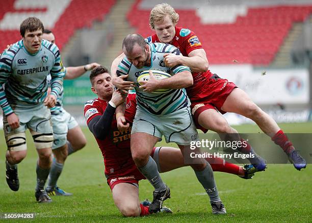 George Chuter of Leicester is tackled by Aled Davies and Owen Williams of Scarlets during the LV= Cup match between Scarlets and Leicester Tigers at...