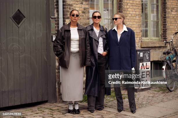Hanna MW wears a black leather jacket, grey skirt, and white shirt and Darja Barannik wears a navy coat, Loewe knit and Tine Andrea wears a blue...
