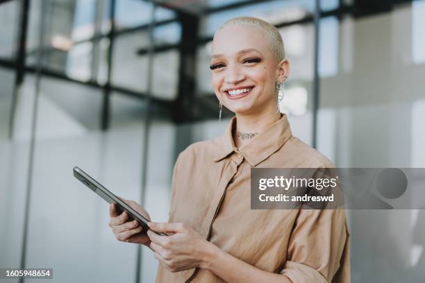 portrait of a hipster business woman holding digital tablet - completely bald stock pictures, royalty-free photos & images