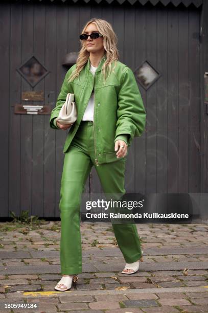 Guest wears a green leather jacket, pants, and white bag outside Remain during the Copenhagen Fashion Week Spring/Summer 2024 on August 8, 2023 in...