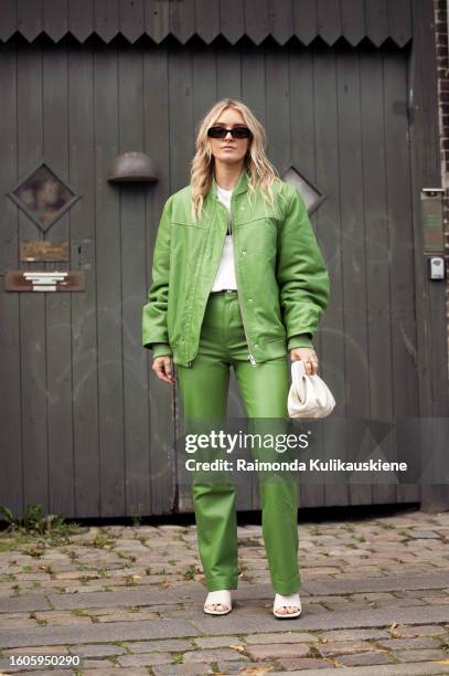 Guest wears a green leather jacket, pants, and white bag outside Remain during the Copenhagen Fashion Week Spring/Summer 2024 on August 8, 2023 in...