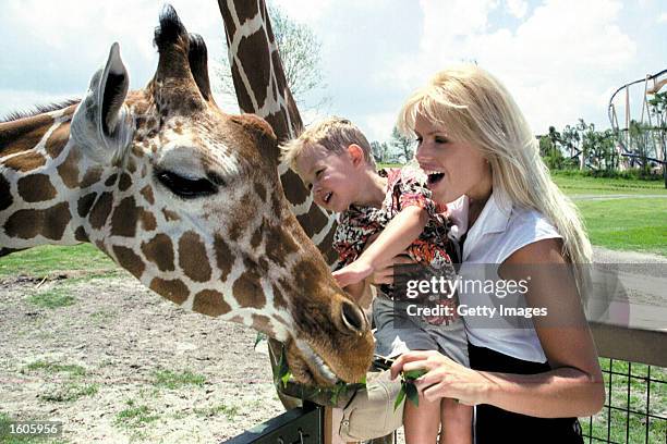 Actress Gena Lee Nolin and her 3-year-old son Spencer greet a giraffe at Busch Gardens Tampa Bay''s Serengeti Plain June 30, 2000 in Tampa, FL.