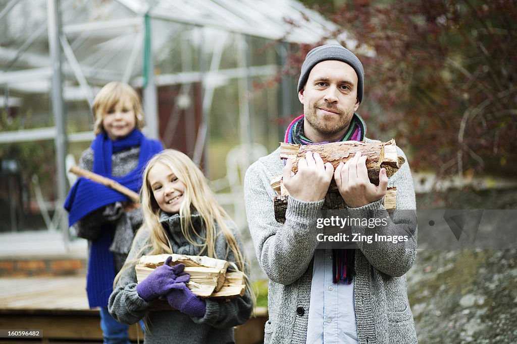 Father and children carrying logs