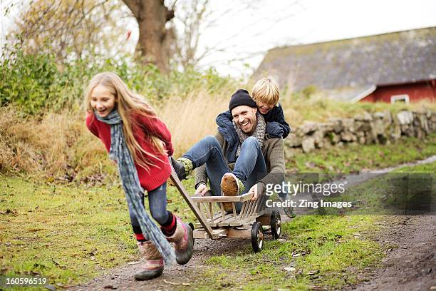 father and children playing with go cart - two kids playing with hose stock-fotos und bilder