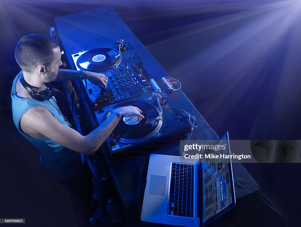 Male DJ Using Decks and Laptop